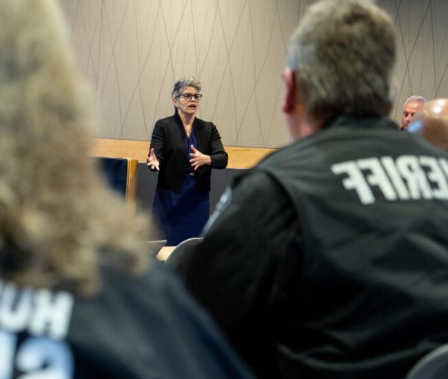 Faculty member instructing class with two class mates wearing sheriff uniform jackets.