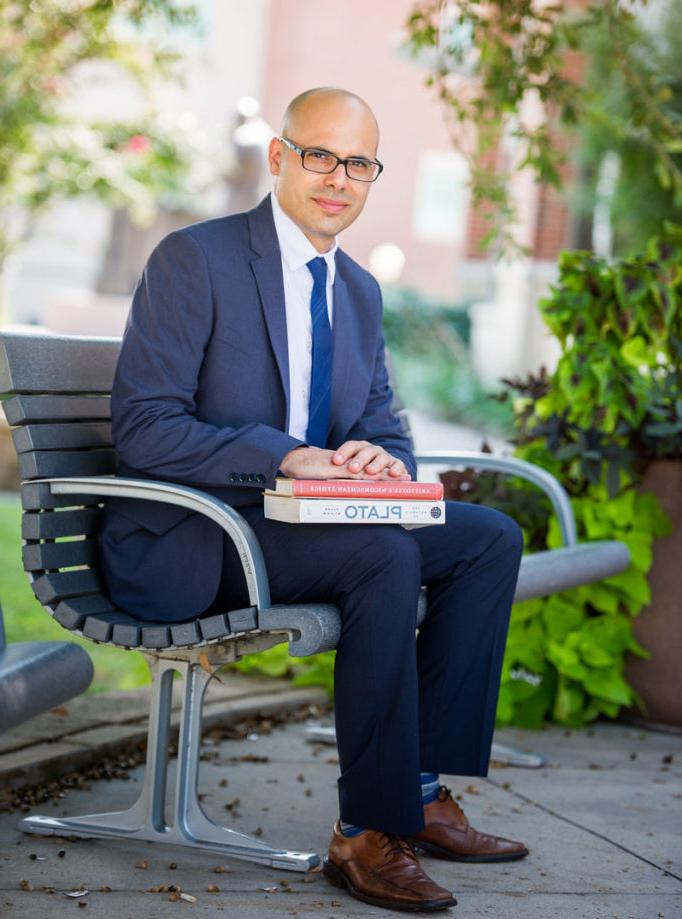 Dr. Mark Menaldo siting on a bench on campus.