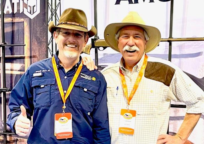 Two men wearing western hats pose together for a photo.